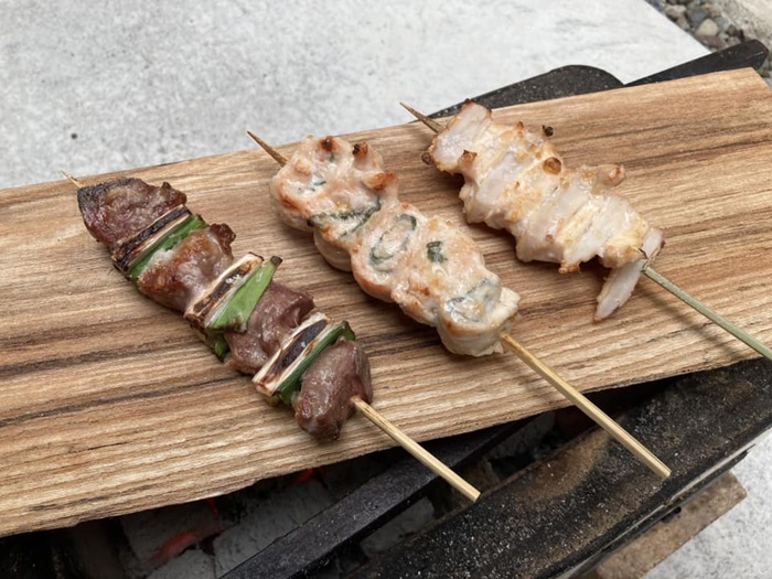 屋外で焼いた焼き鳥を木の皿に置いたところ