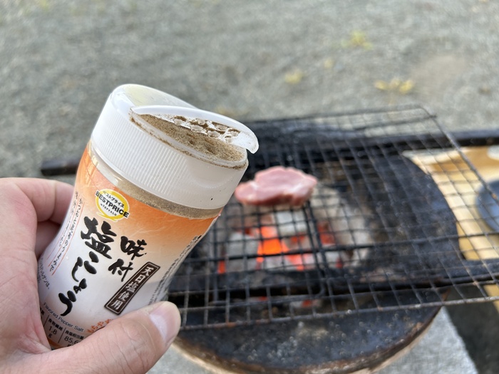七輪で肉を炭火焼きする際に塩コショウを使用している様子
